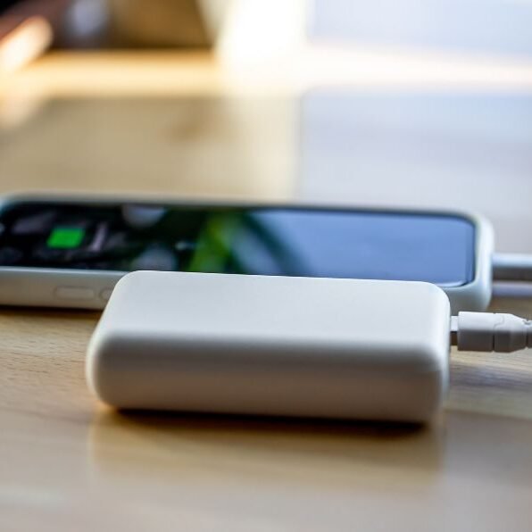 The smartphone is charged from a small white power bank via a cord.